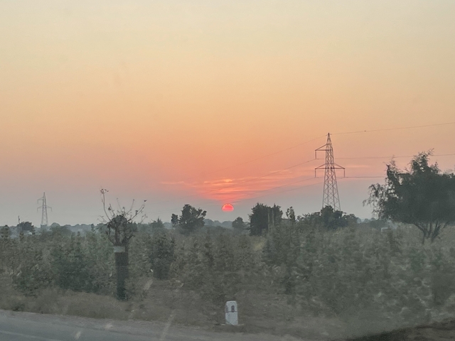 Sunset over a rural landscape with power lines.