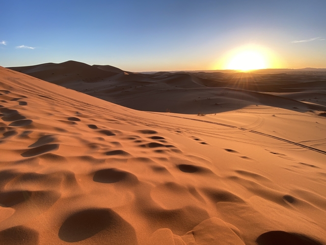 Expansive sand dunes during sunset with clear sky.