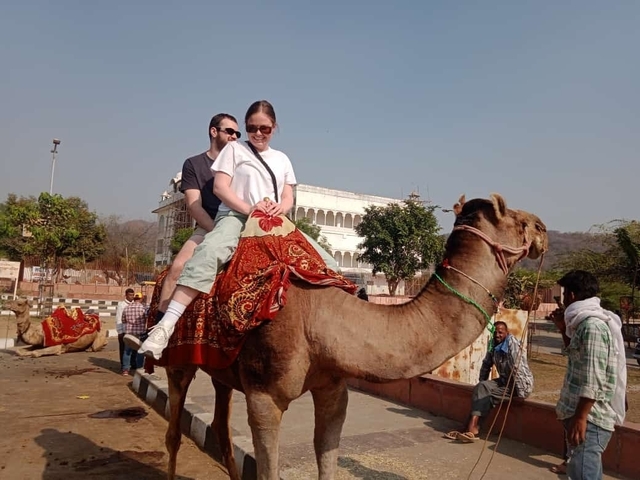 Two people riding a camel in a city setting