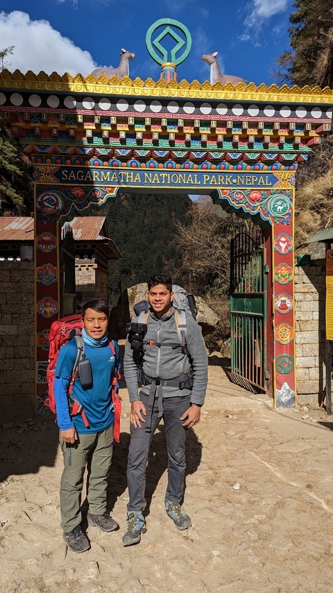 Two hikers standing at a decorated entrance gate
