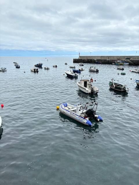 Boats floating on a calm sea under a cloudy sky.