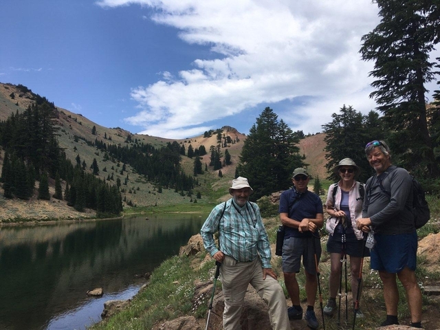 Group of people posing near a lake in a mountainous area.