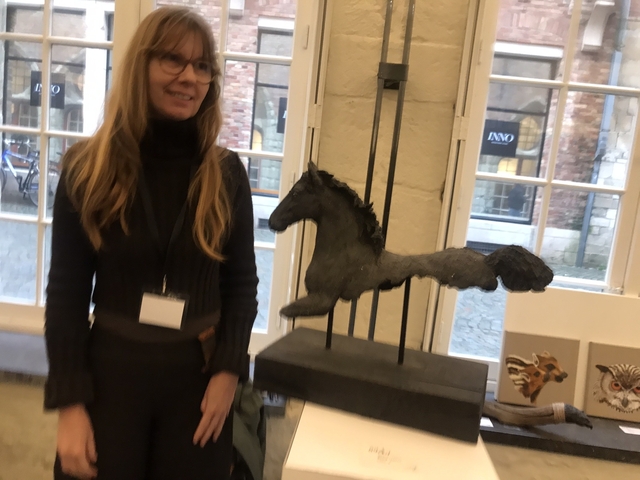       Person standing next to a sculpture inside a building.
  
