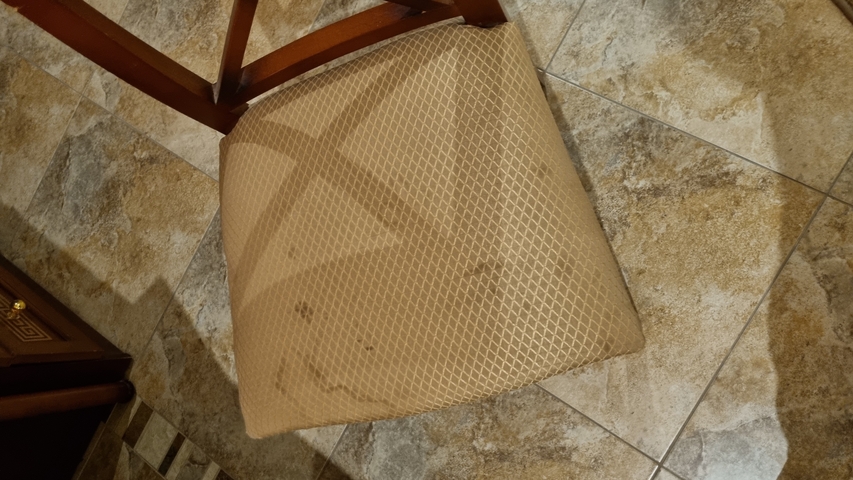       Stained chair in a room with tiled floor.
  