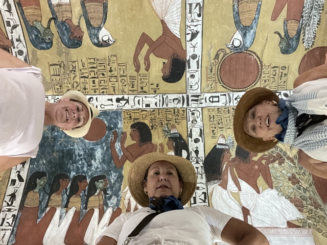 Three people looking up at Egyptian mural ceiling.