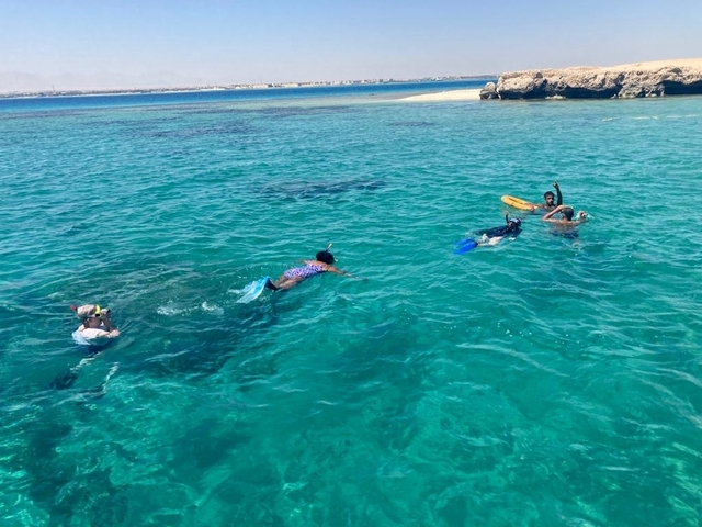 Group of people snorkeling in clear blue water.
