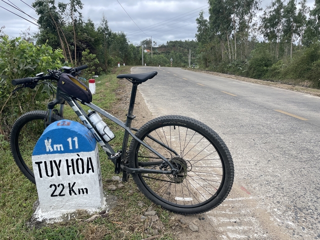       Bicycle next to a road marker indicating distance to Tuy Hoa.
  