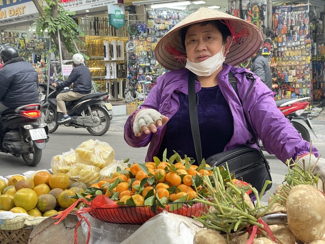       Street vendor selling fruits on a busy street.
  