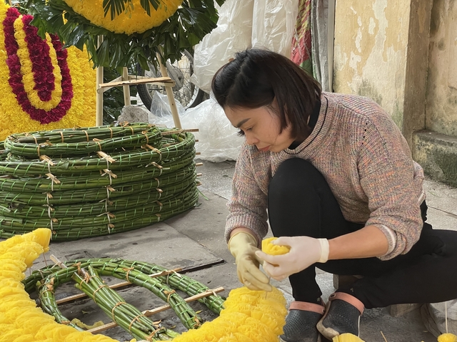       Person crafting decorations with yellow flowers.
  