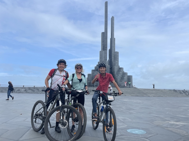       Cyclists posing in front of a monument.
  
