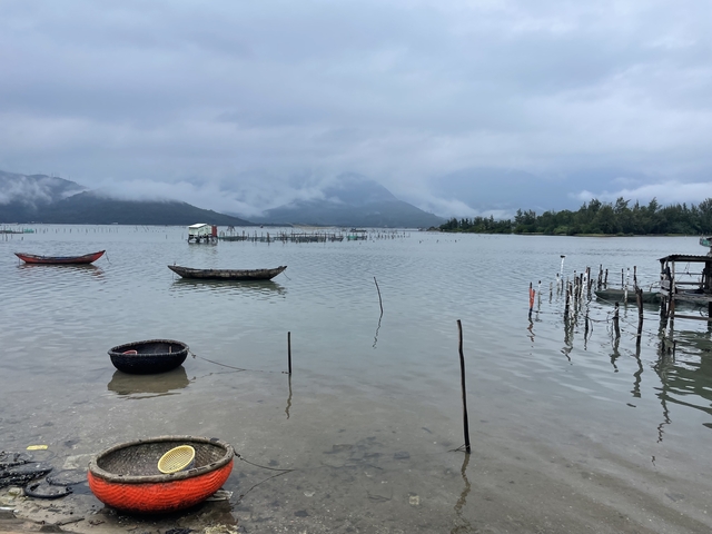       Calm fishing waters with small boats and misty mountains.
  