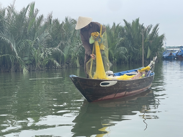       Person fishing with a traditional net on a boat.
  