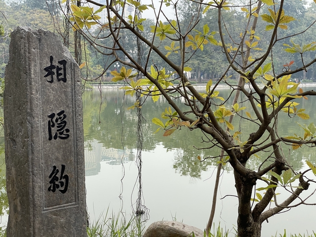       Stone marker with text next to a lake and foliage.
  