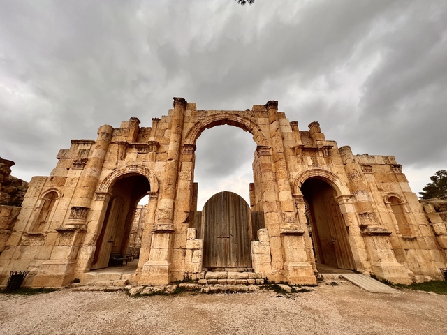      Stone archway with dramatic sky in a historical site.
  