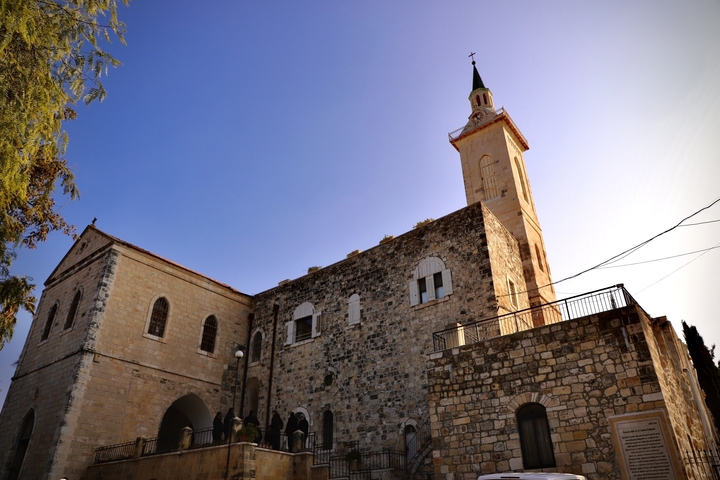       Exterior of a stone building with a tower under a clear sky.
  