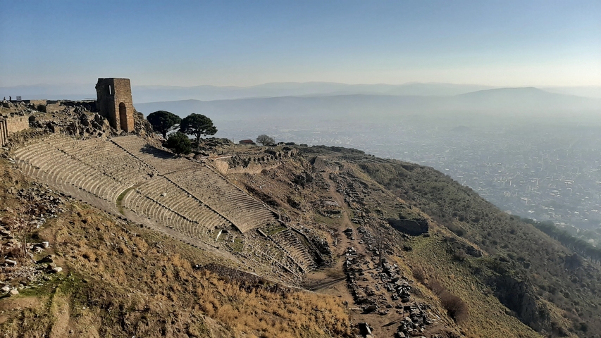       Ancient amphitheater ruins with a vast city in the background.
  