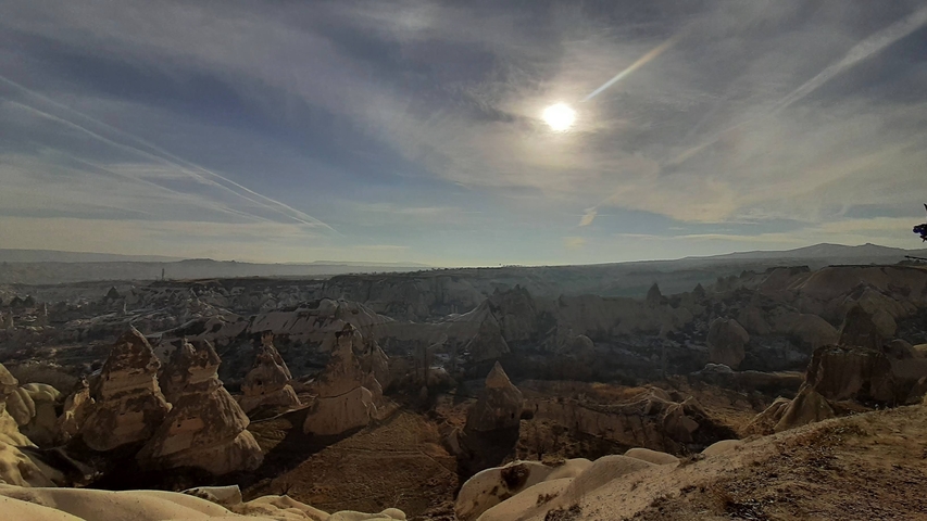       Panoramic view of unique geological formations under a bright sky.
  
