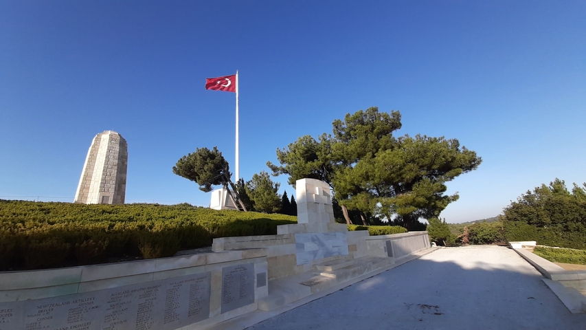       War memorial with a tall monument and a Turkish flag.
  