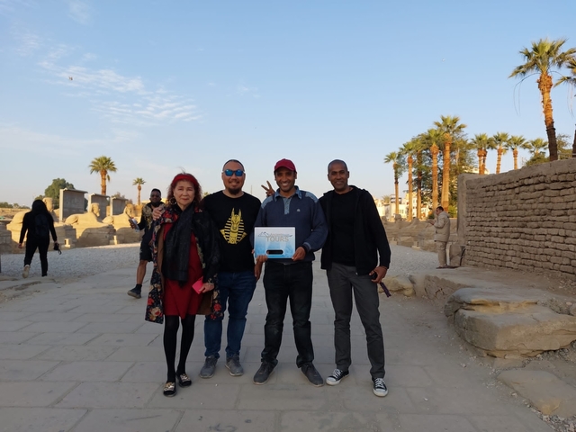       Group of tourists posing together in an ancient ruins site.
  