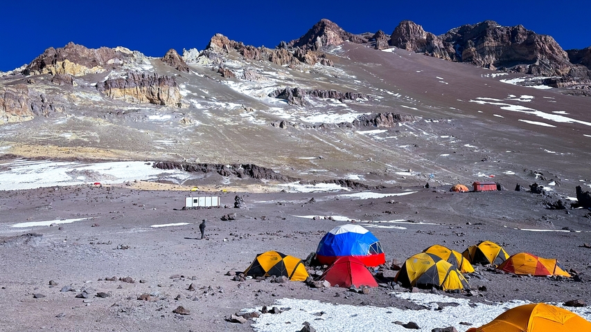       Colorful tents in a rocky mountain campsite.
  