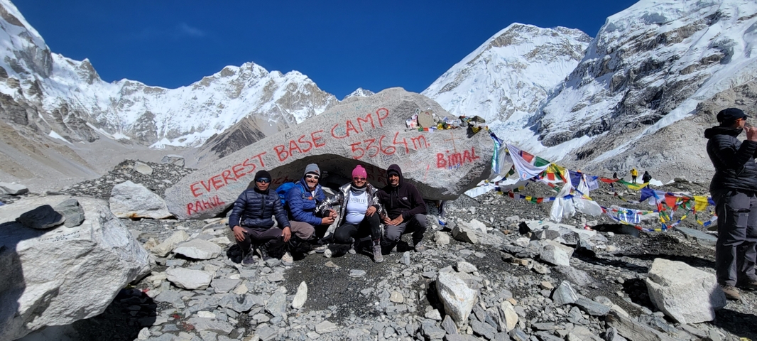       Group of hikers posing at Everest Base Camp sign.
  