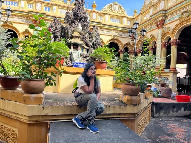       Person sitting surrounded by lush greenery in a courtyard.
  