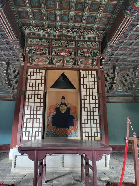 Traditional Korean building with intricate designs and a portrait.