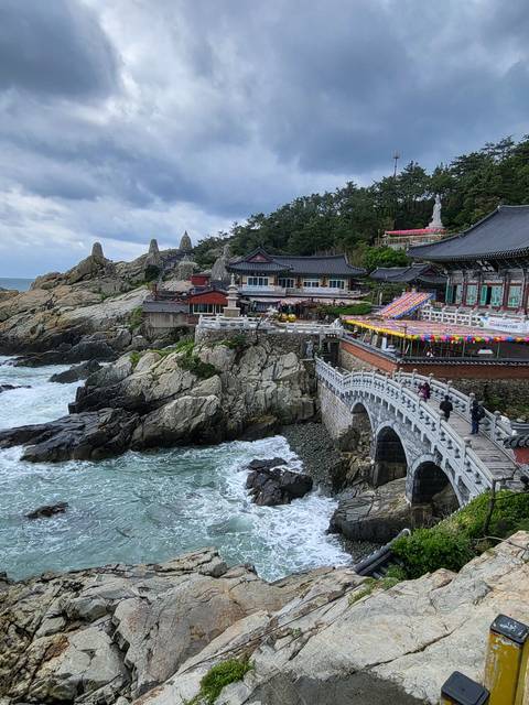 Temple on a rocky coastline with ocean waves.