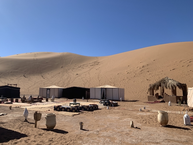 A desert campsite with tents and sand dunes.