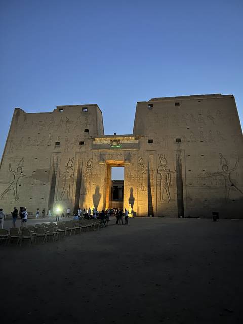       Large temple entrance with people and evening lighting.
  