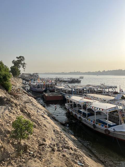       Brightly decorated boats docked by a river bank.
  