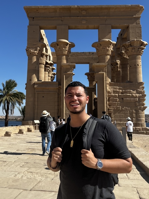       Person posing in front of an ancient Egyptian temple.
  