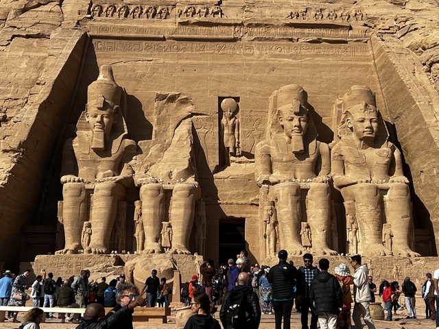       Crowd of people in front of enormous Egyptian statues.
  