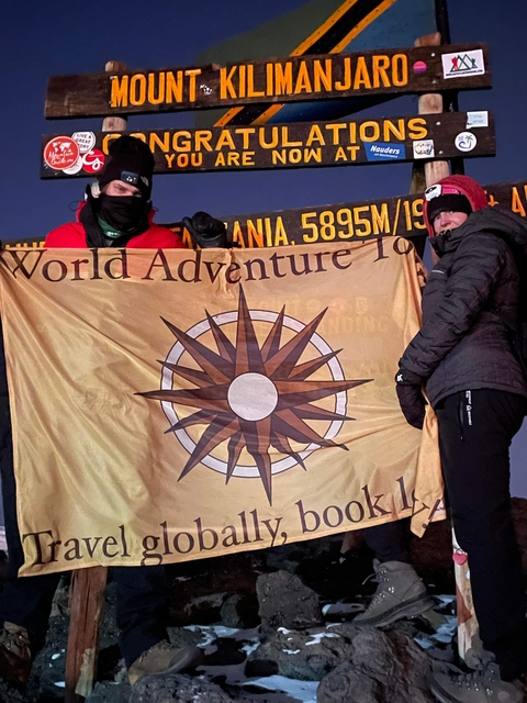 Two people holding a flag at a high altitude.