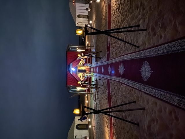 Outdoor tent setup on sand with lighting.