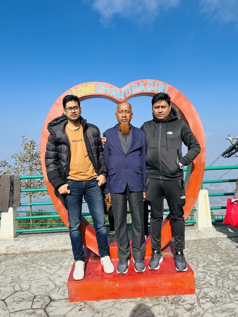       Three men posing in front of a heart-shaped sculpture.
  