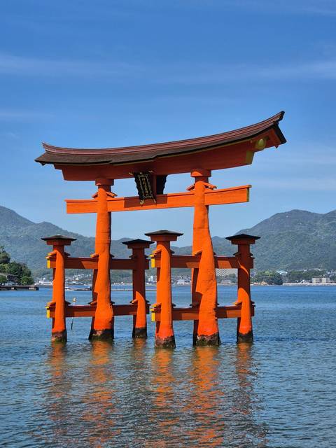       Crowded area with famous red torii gate at the shoreline.
  