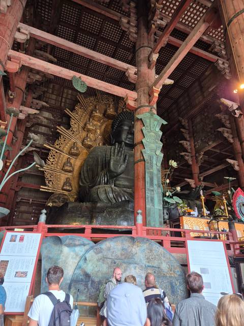       People viewing a large indoor statue.
  