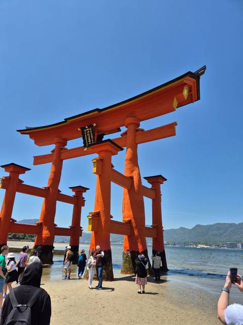       Famous red torii gate by the water with visitors.
  