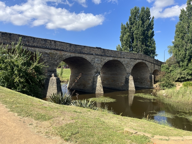 Stone bridge over a river with clear skies.