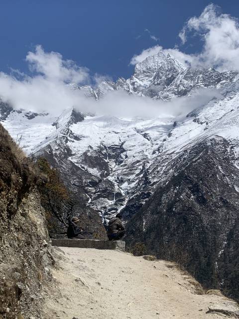A snow-covered mountain peak with a hiking path and people on the trail.