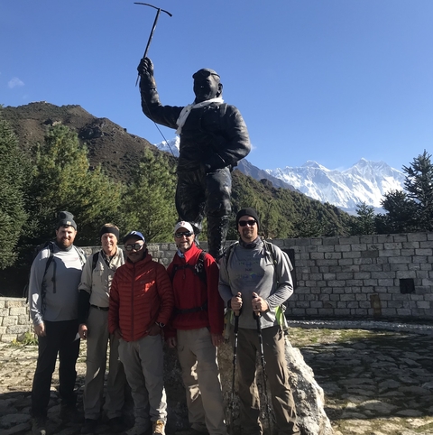 Group of hikers posing with a mountain statue