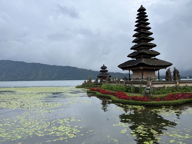       Temple complex by a lake with mountains in the background.
  