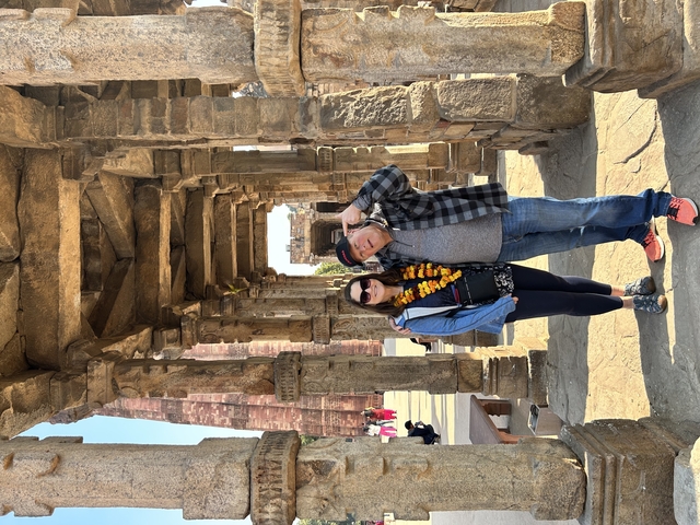       Couple posing in a historic corridor with floral garlands.
  