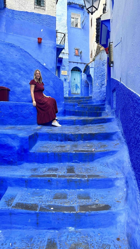 Person sitting on blue-painted steps in Chefchaouen.
