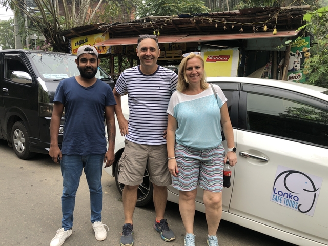 Three people posing in front of a car with Lanka Safe Tours signage.