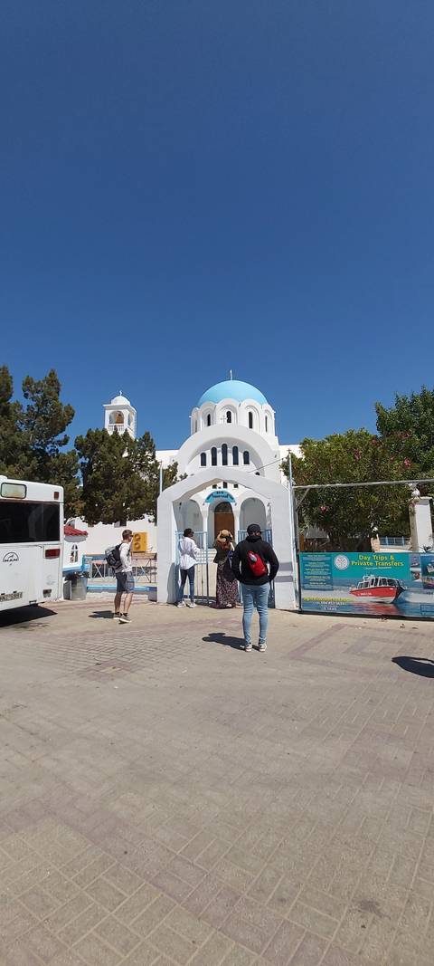 A street scene with people walking near a church with a blue dome.