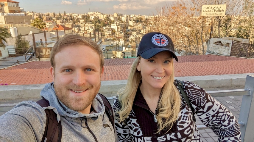 Couple with a cityscape in the background and blue skies.