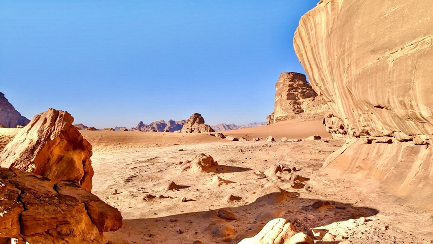 Expansive desert with rock formations and clear skies.