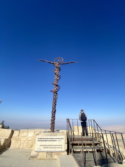 Sculpture of a staff with snakes in front of a clear blue sky.